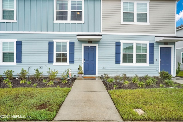entrance to property featuring a lawn and board and batten siding