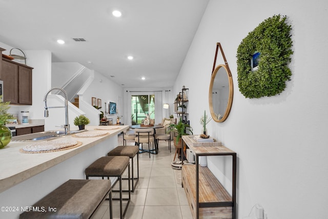 kitchen featuring recessed lighting, a sink, a kitchen bar, visible vents, and light countertops