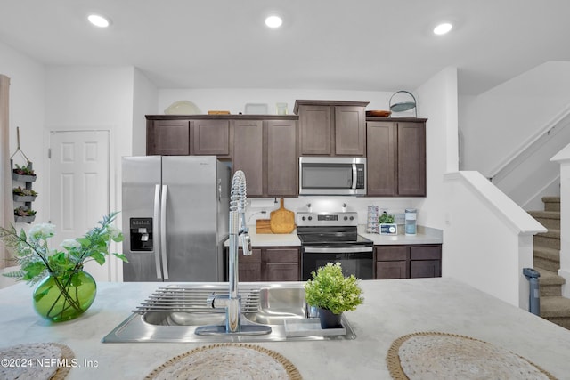 kitchen with stainless steel appliances, dark brown cabinets, light countertops, and a sink