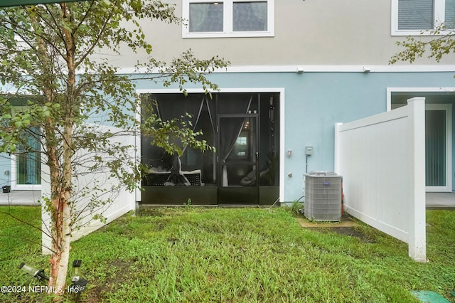 rear view of house with central air condition unit, a yard, and stucco siding