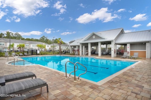 community pool featuring a residential view, a patio, and fence