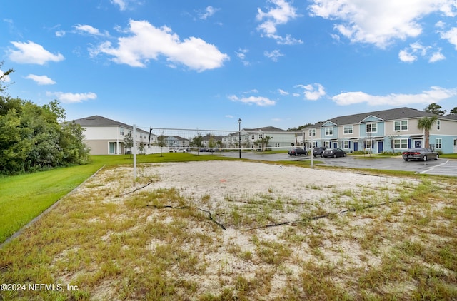 surrounding community featuring a lawn, uncovered parking, a residential view, and volleyball court