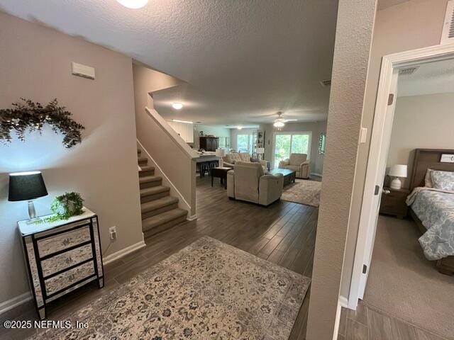 corridor featuring visible vents, wood finished floors, baseboards, stairway, and a textured ceiling