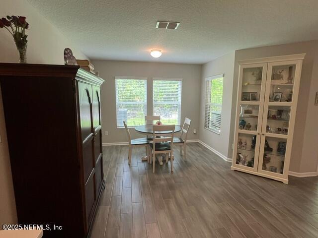 dining space with dark wood-style flooring, baseboards, and a textured ceiling