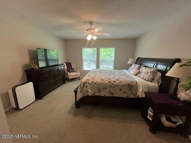 bedroom with a ceiling fan and light carpet
