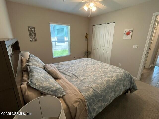 bedroom featuring baseboards, ceiling fan, wood finished floors, and a closet