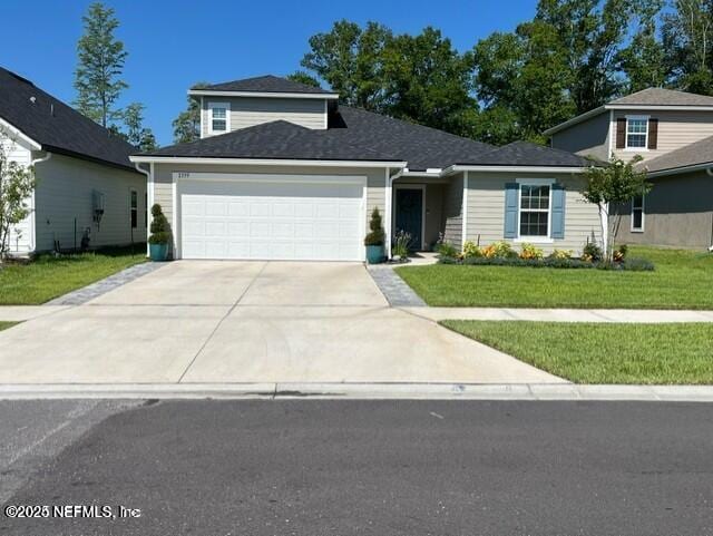 view of front facade with concrete driveway, an attached garage, and a front lawn