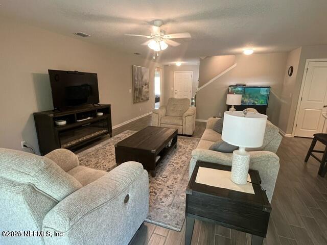 living area featuring visible vents, baseboards, ceiling fan, and wood finished floors