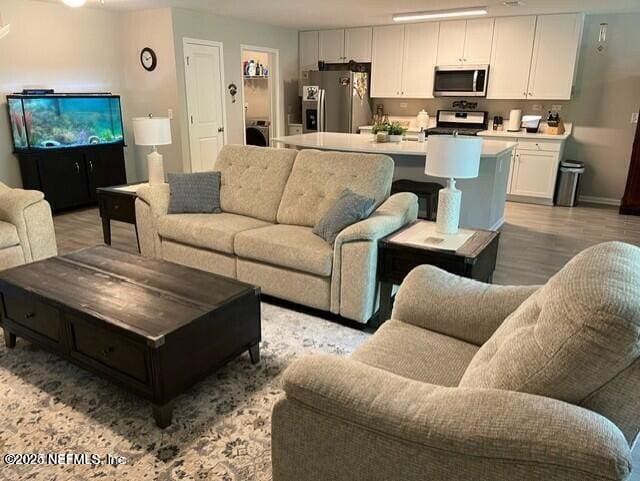 living area with baseboards, light wood finished floors, and washer / clothes dryer