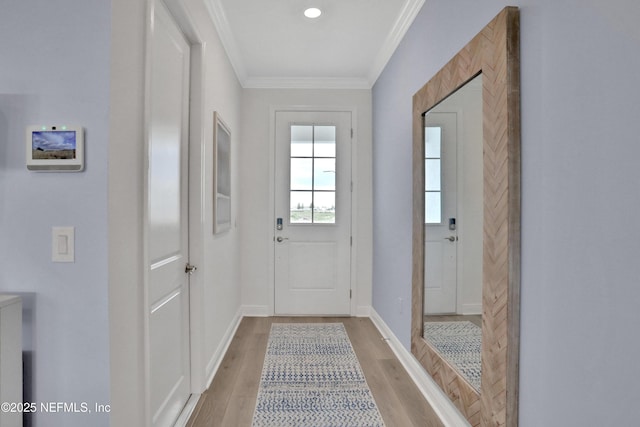 doorway to outside with baseboards, crown molding, and light wood-style flooring
