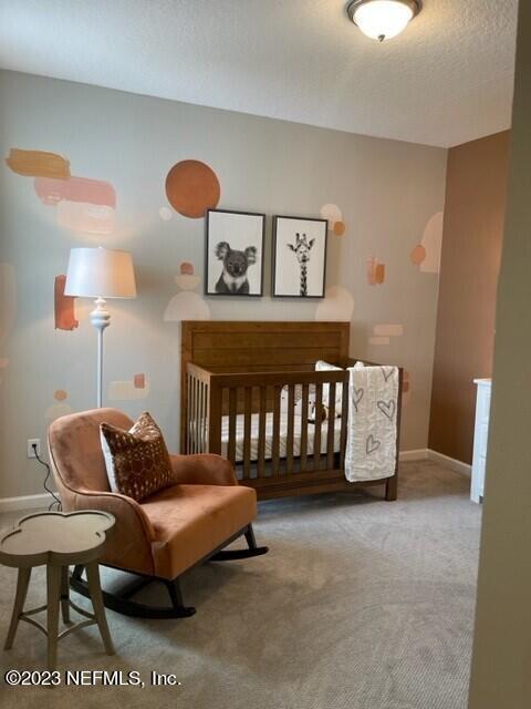 bedroom with a textured ceiling, carpet flooring, and baseboards