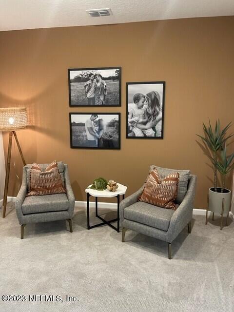sitting room featuring light colored carpet, visible vents, and baseboards