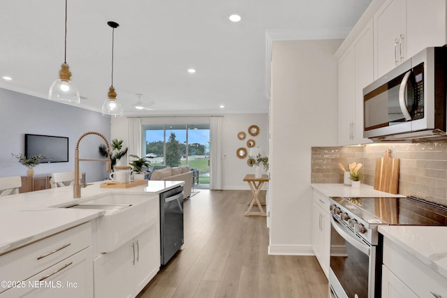kitchen featuring appliances with stainless steel finishes, open floor plan, decorative backsplash, and crown molding