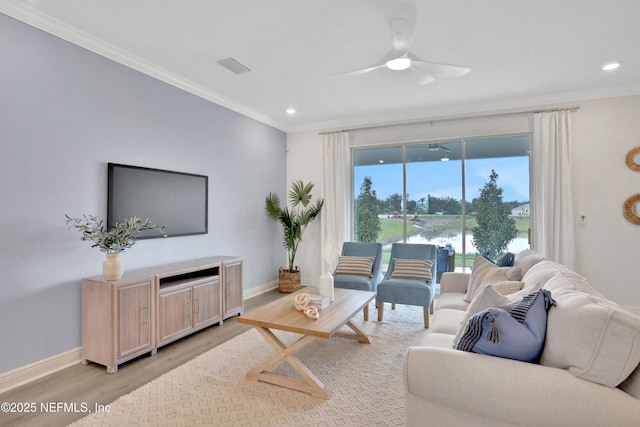 living area with light wood-style floors, a ceiling fan, ornamental molding, and baseboards