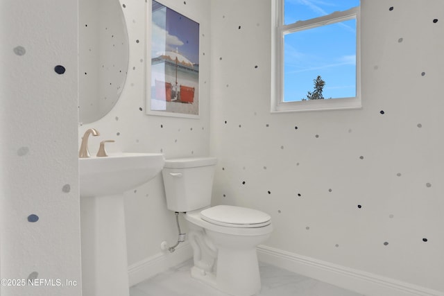 bathroom with baseboards, toilet, and marble finish floor