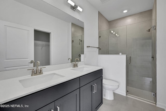 bathroom featuring toilet, double vanity, a sink, and a shower stall