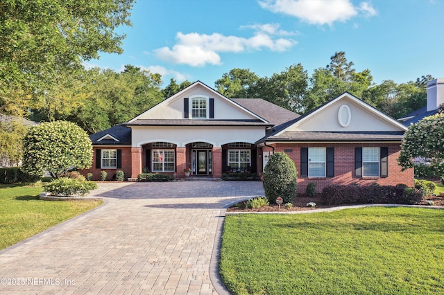 traditional home featuring brick siding, decorative driveway, and a front lawn