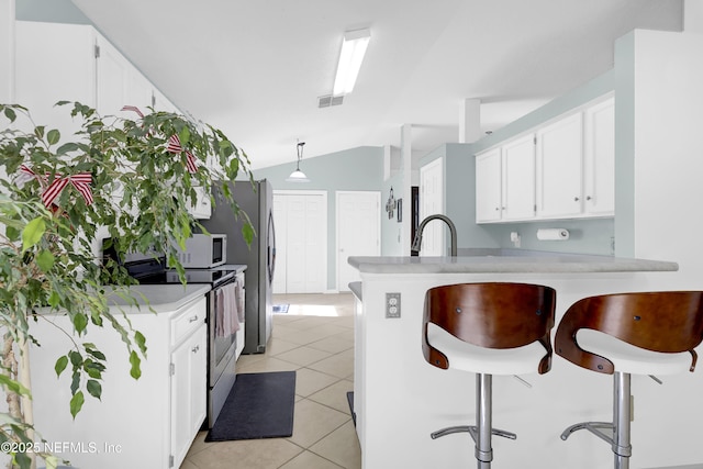 1558 Roseberry Ct, Fleming Island, FL 32003 - kitchen with appliances with stainless steel finishes, light countertops, white cabinetry, a peninsula, and lofted ceiling