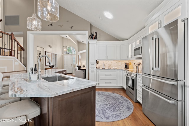 1576 Linkside Dr, Fleming Island, FL 32003 - kitchen featuring appliances with stainless steel finishes, a sink, lofted ceiling, decorative backsplash, and white cabinets