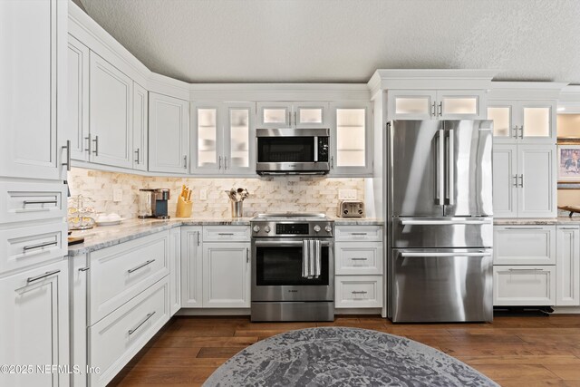 1576 Linkside Dr, Fleming Island, FL 32003 - kitchen with stainless steel appliances, white cabinets, light stone counters, decorative backsplash, and a textured ceiling