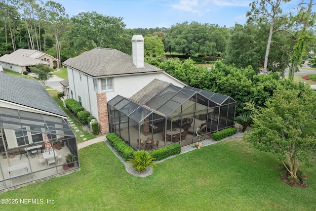 1576 Linkside Dr, Fleming Island, FL 32003 - rear view of house featuring a chimney, a patio, a lawn, roof with shingles, and glass enclosure