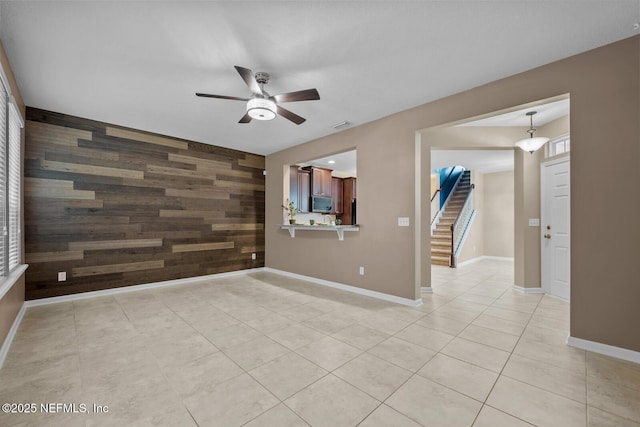 133 San Briso Way, Saint Augustine, FL 32092 - unfurnished room with wooden walls, a ceiling fan, an accent wall, light tile patterned floors, and stairs