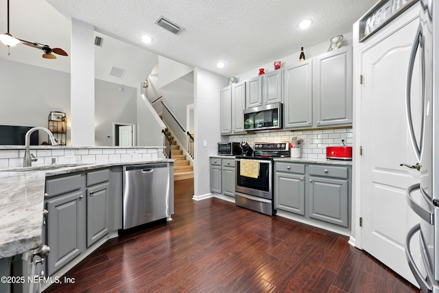 2427 Green Glade Ct, Fleming Island, FL 32003 - kitchen with stainless steel appliances, gray cabinetry, a sink, tasteful backsplash, and a textured ceiling