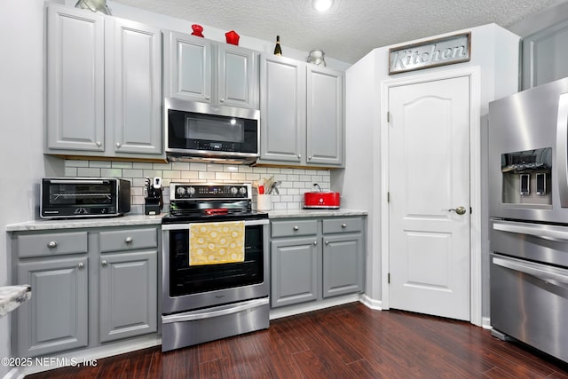 2427 Green Glade Ct, Fleming Island, FL 32003 - kitchen with stainless steel appliances, gray cabinets, dark wood-style flooring, decorative backsplash, and light countertops