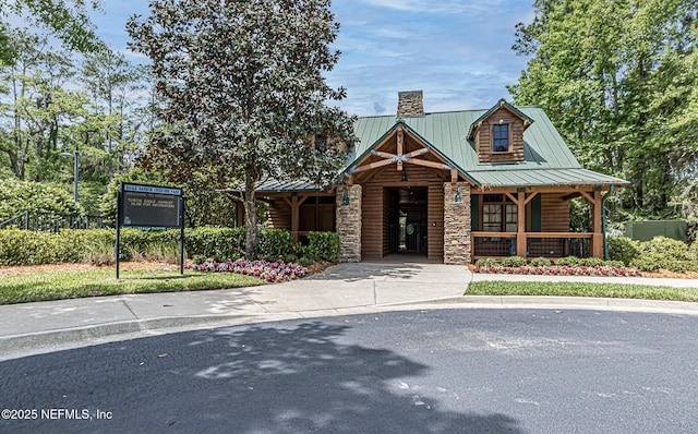 2427 Green Glade Ct, Fleming Island, FL 32003 - view of front facade with a chimney, a standing seam roof, a porch, stone siding, and metal roof