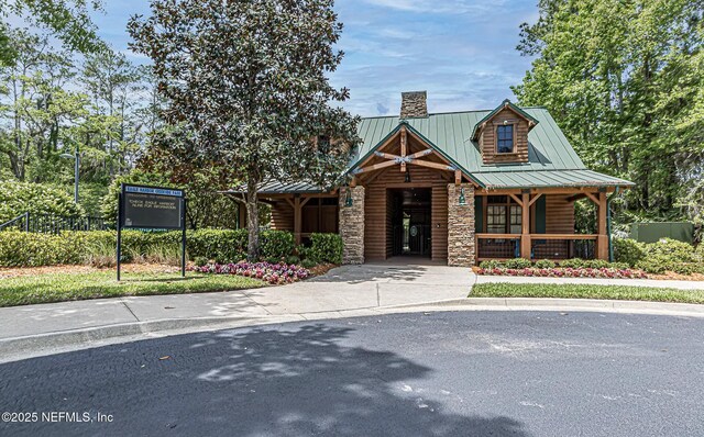 2427 Green Glade Ct, Fleming Island, FL 32003 - view of front facade with a chimney, a standing seam roof, a porch, stone siding, and metal roof