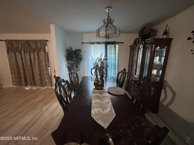 dining space with a textured ceiling, a chandelier, and wood finished floors