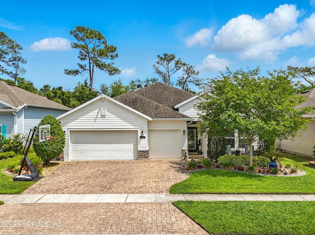 view of front of home featuring roof with shingles, stone siding, a garage, a front yard, and decorative driveway