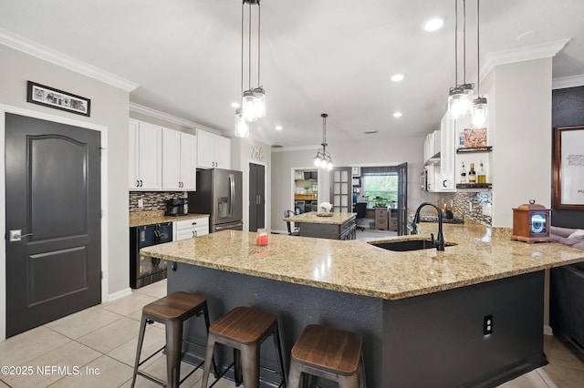 kitchen featuring crown molding, beverage cooler, stainless steel fridge, a center island, and a sink