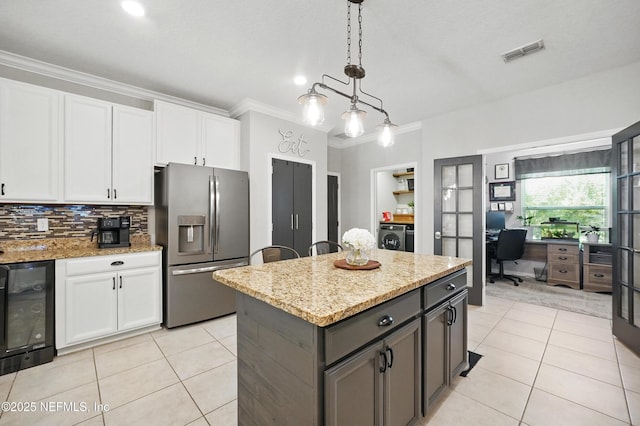 kitchen featuring ornamental molding, beverage cooler, stainless steel fridge, independent washer and dryer, and light tile patterned floors