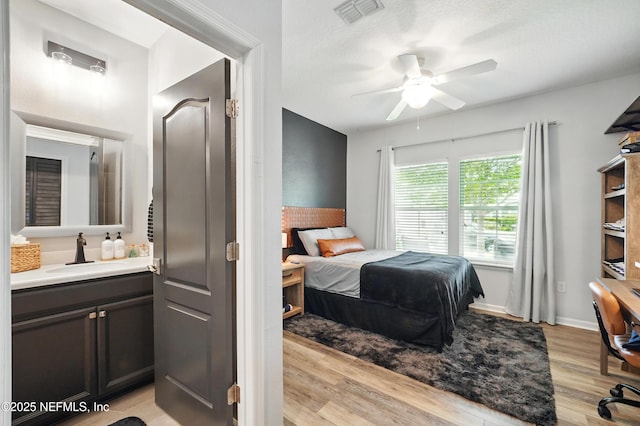 bedroom with visible vents, a sink, light wood-style flooring, and ceiling fan