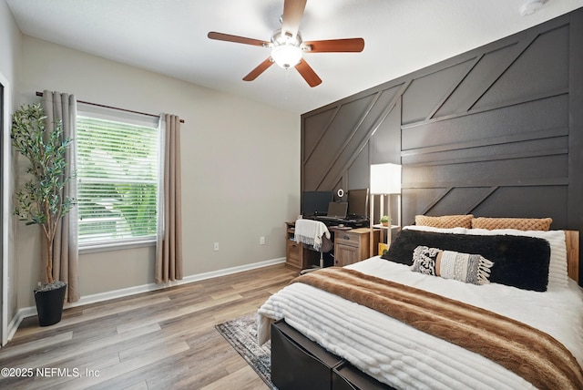 bedroom with a ceiling fan, baseboards, and light wood-type flooring