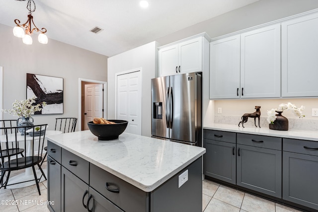 kitchen with gray cabinets, stainless steel refrigerator with ice dispenser, visible vents, a center island, and light tile patterned floors
