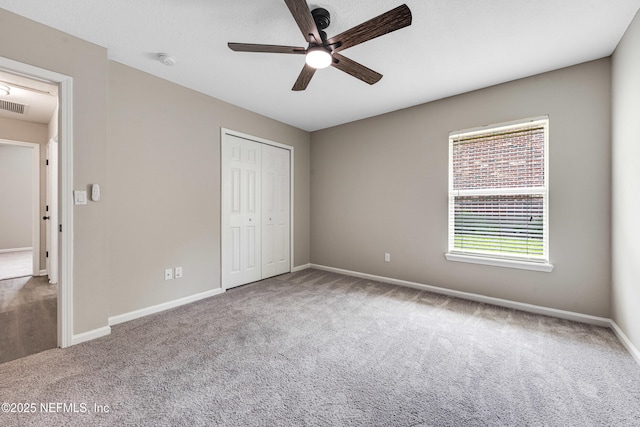 unfurnished bedroom featuring baseboards, carpet flooring, a closet, and multiple windows
