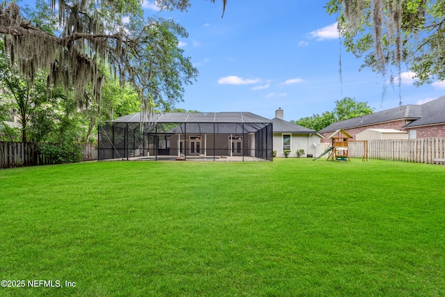 back of property featuring a playground, a chimney, a yard, and a fenced backyard