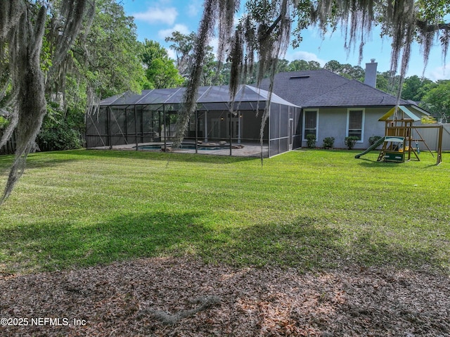 back of house with a chimney, an outdoor pool, a playground, a yard, and a shingled roof