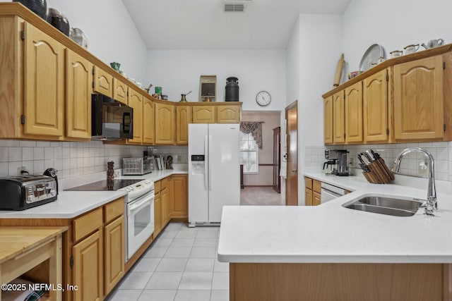 kitchen featuring decorative backsplash, a sink, visible vents, light countertops, and white appliances