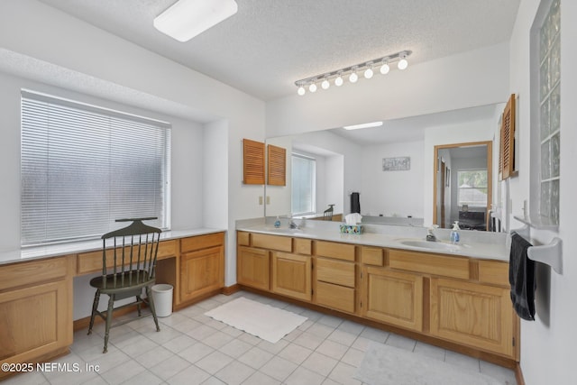 bathroom with double vanity, a textured ceiling, tile patterned floors, and a sink