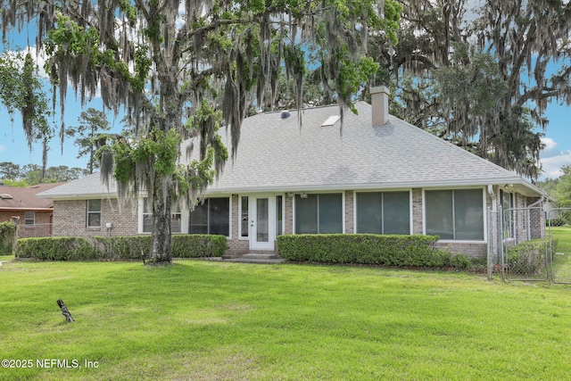 view of front of home featuring a chimney, brick siding, entry steps, and a front lawn