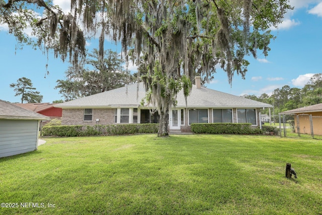 view of front of home featuring a chimney, brick siding, fence, and a front yard