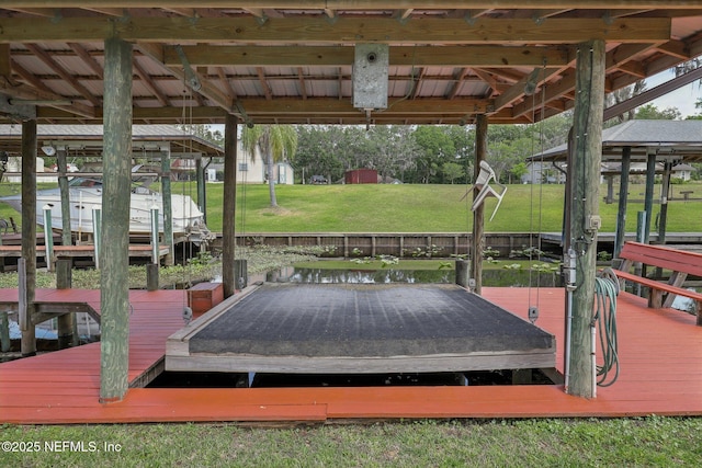 view of dock with boat lift and a lawn
