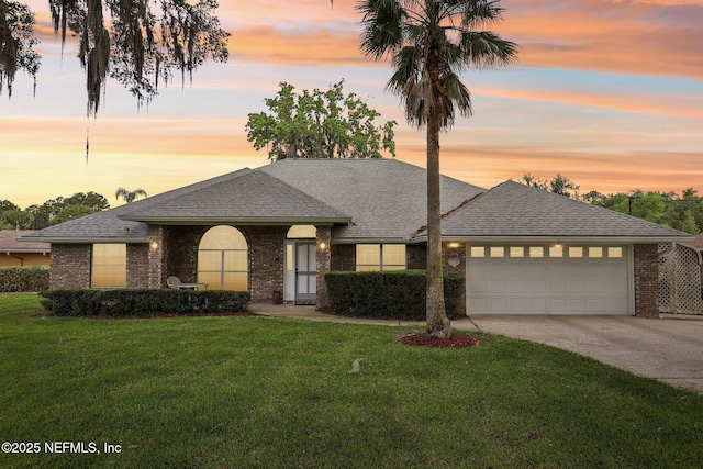 single story home featuring concrete driveway, an attached garage, a shingled roof, and a front lawn