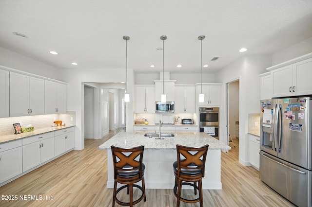 kitchen with a sink, backsplash, white cabinets, and stainless steel appliances