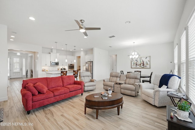 living area with visible vents, light wood-style floors, baseboards, recessed lighting, and ceiling fan with notable chandelier