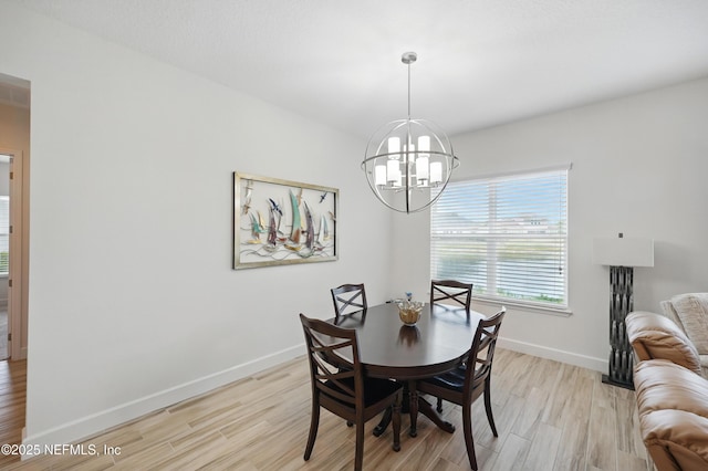 dining space with baseboards, light wood finished floors, and a chandelier