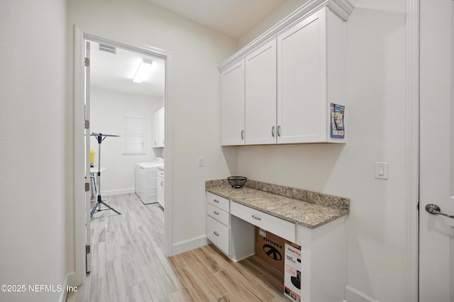 unfurnished office with separate washer and dryer, baseboards, built in study area, and light wood-style floors